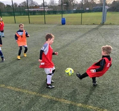 Young players in red bibs playing in a session
